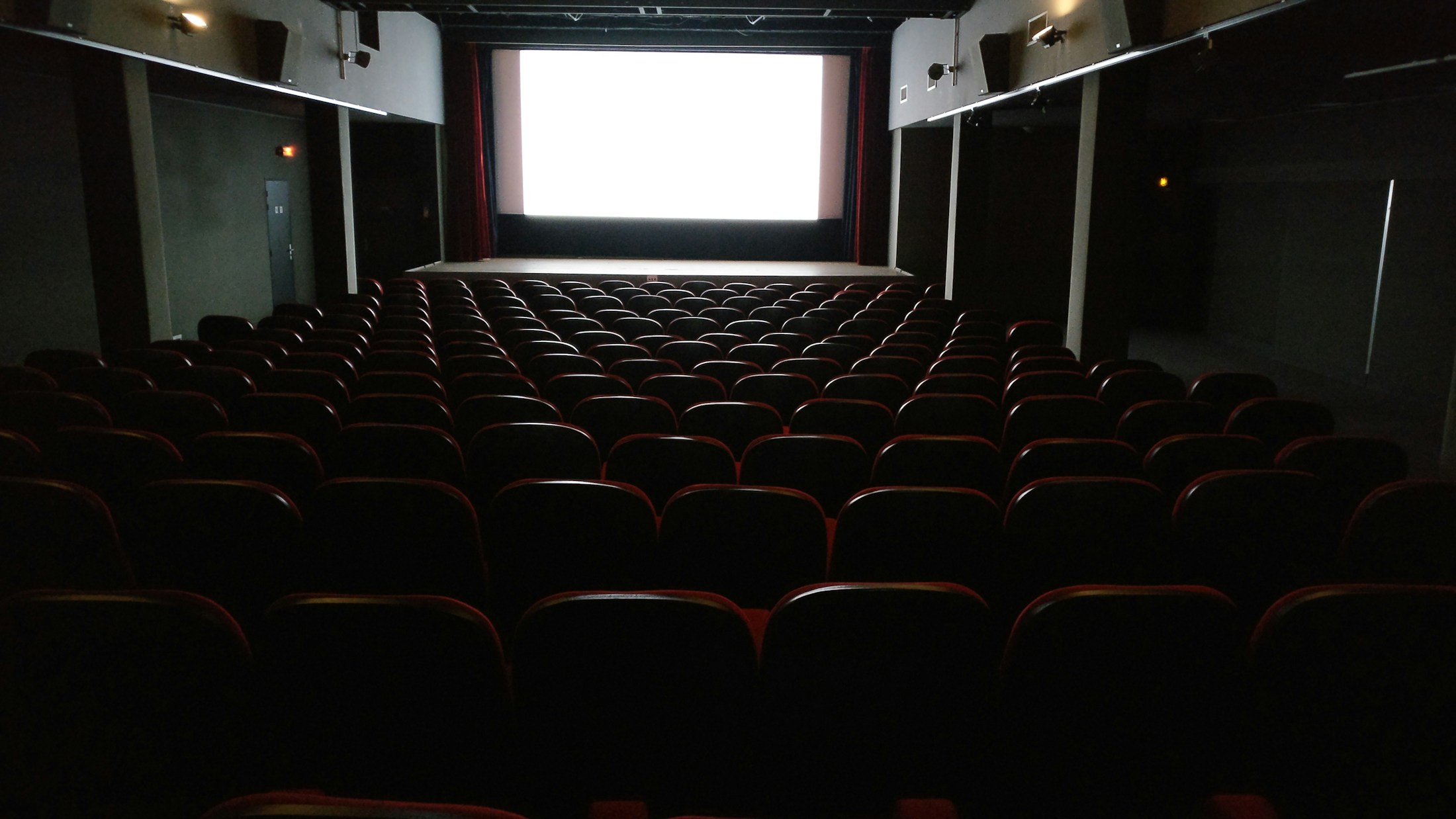 Dark cinema interior with rows of seats and a lit screen